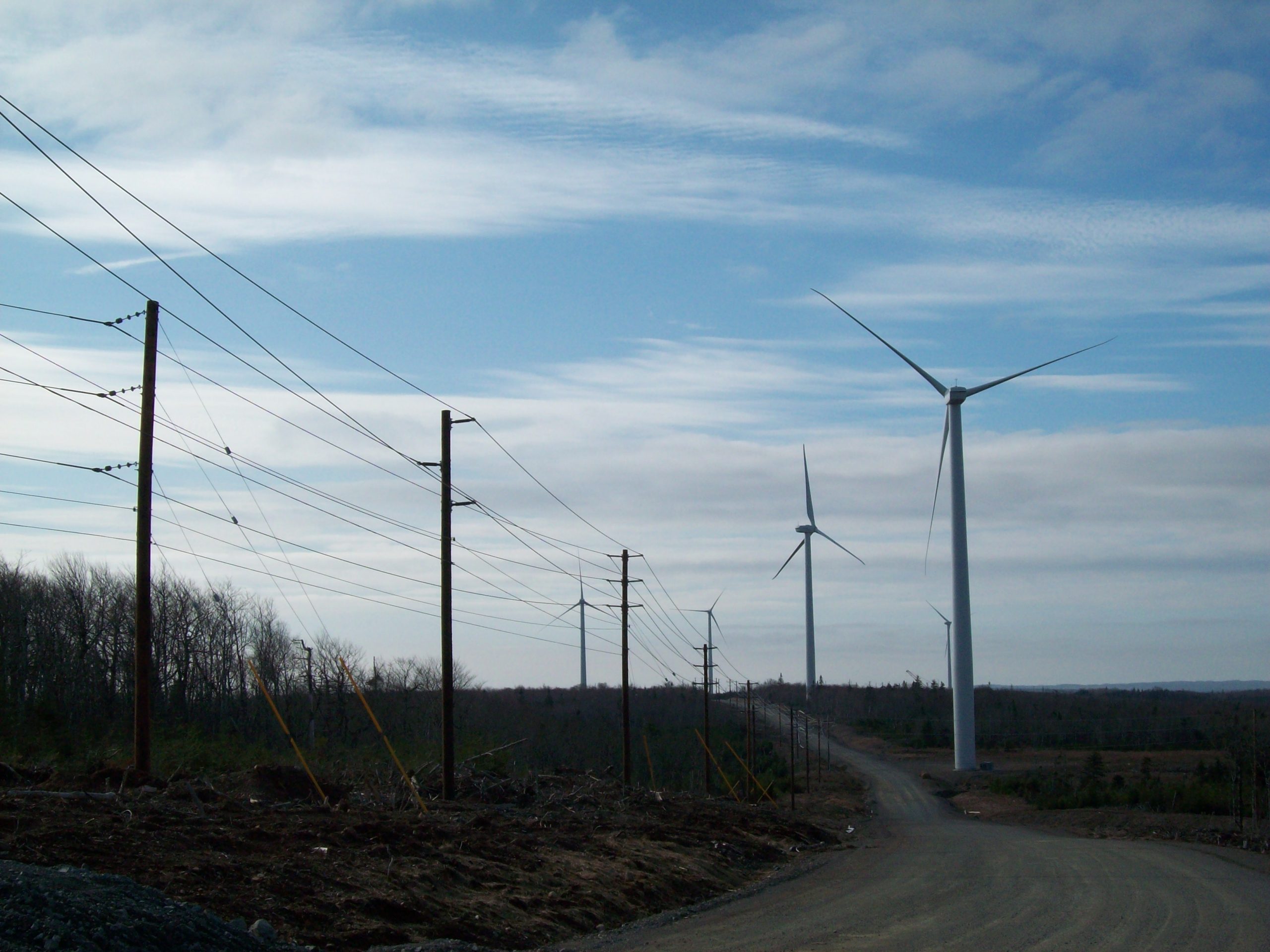 Landscape view of Windmills and Power Lines. Holland Power Services has high voltage solutions for utility, commercial, renewable energy, and industrial customers.